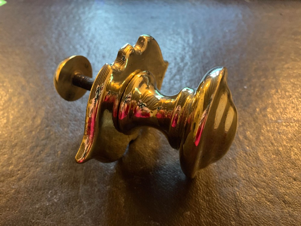 A polished brass Georgian centre door knob featuring an oval handle mounted to a shaped decorative backplate. View IV