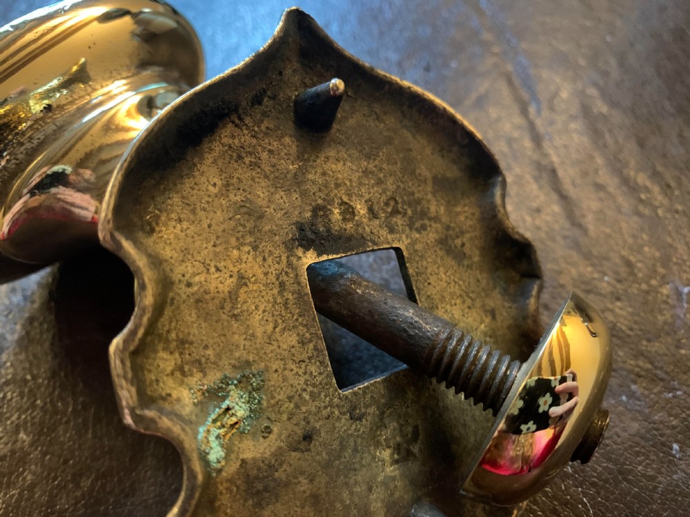 A polished brass Georgian centre door knob featuring an oval handle mounted to a shaped decorative backplate. View VI