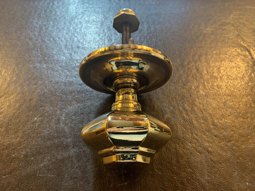 A polished brass octagonal centre door knob with a circular backplate and threaded bolt.