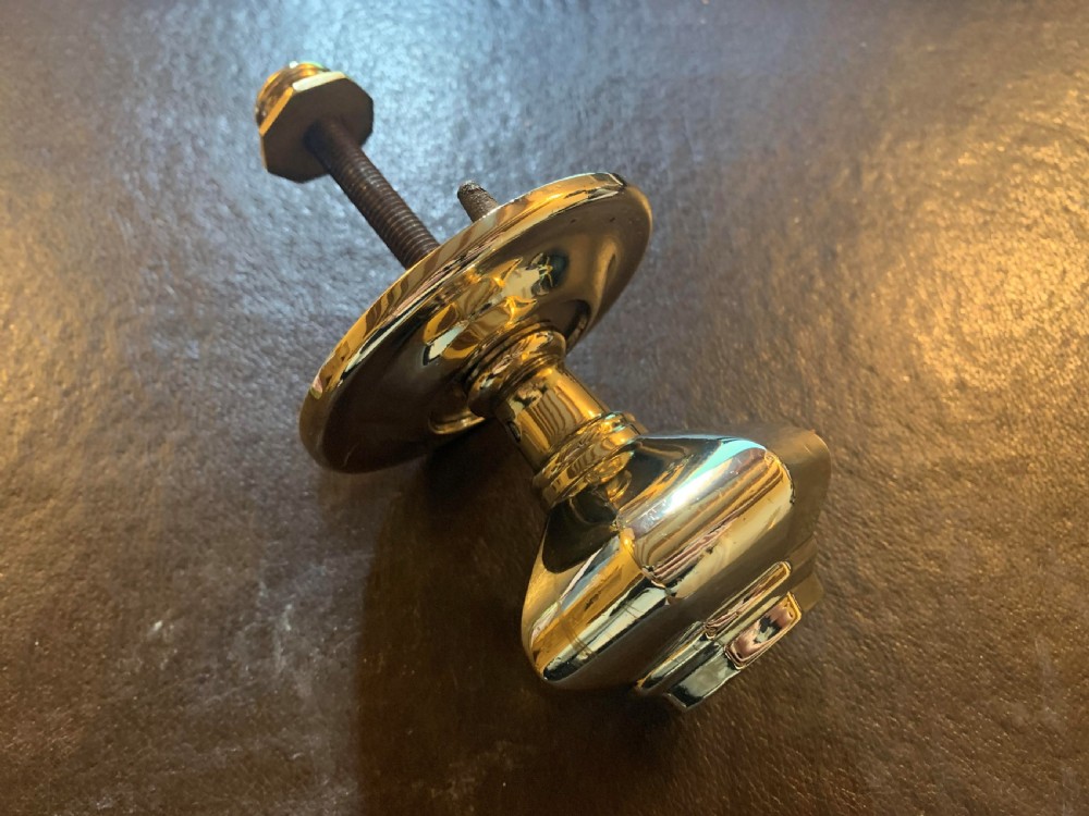 A polished brass octagonal centre door knob with a circular backplate and threaded bolt. View II