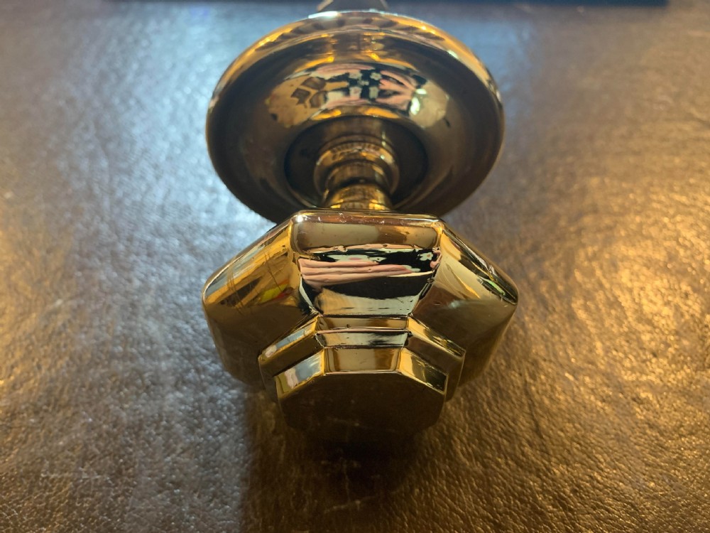 A polished brass octagonal centre door knob with a circular backplate and threaded bolt. View III