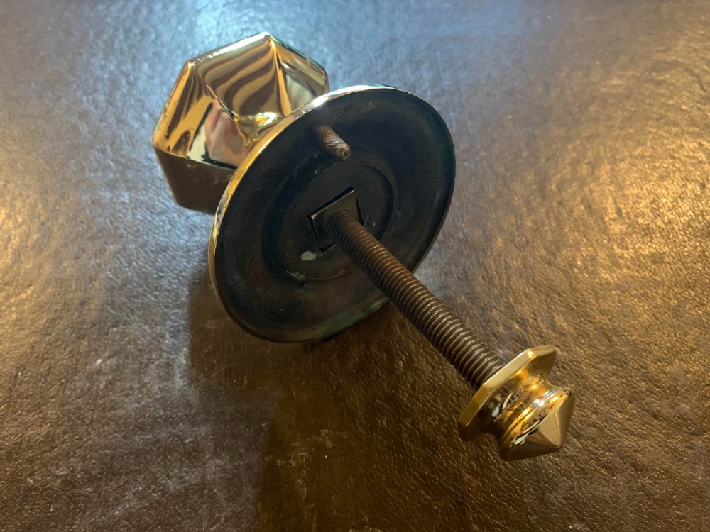 A polished brass octagonal centre door knob with a circular backplate and threaded bolt. View IV