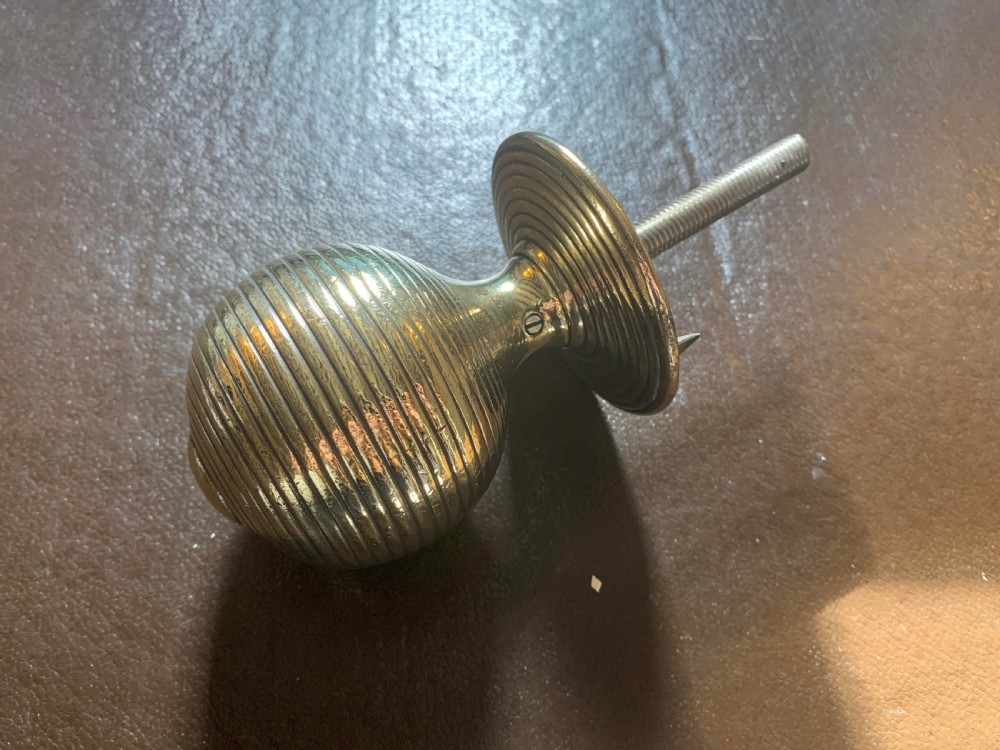 A solid brass Victorian beehive centre door knob with concentric reeded ridges and an attached mounting bolt.
