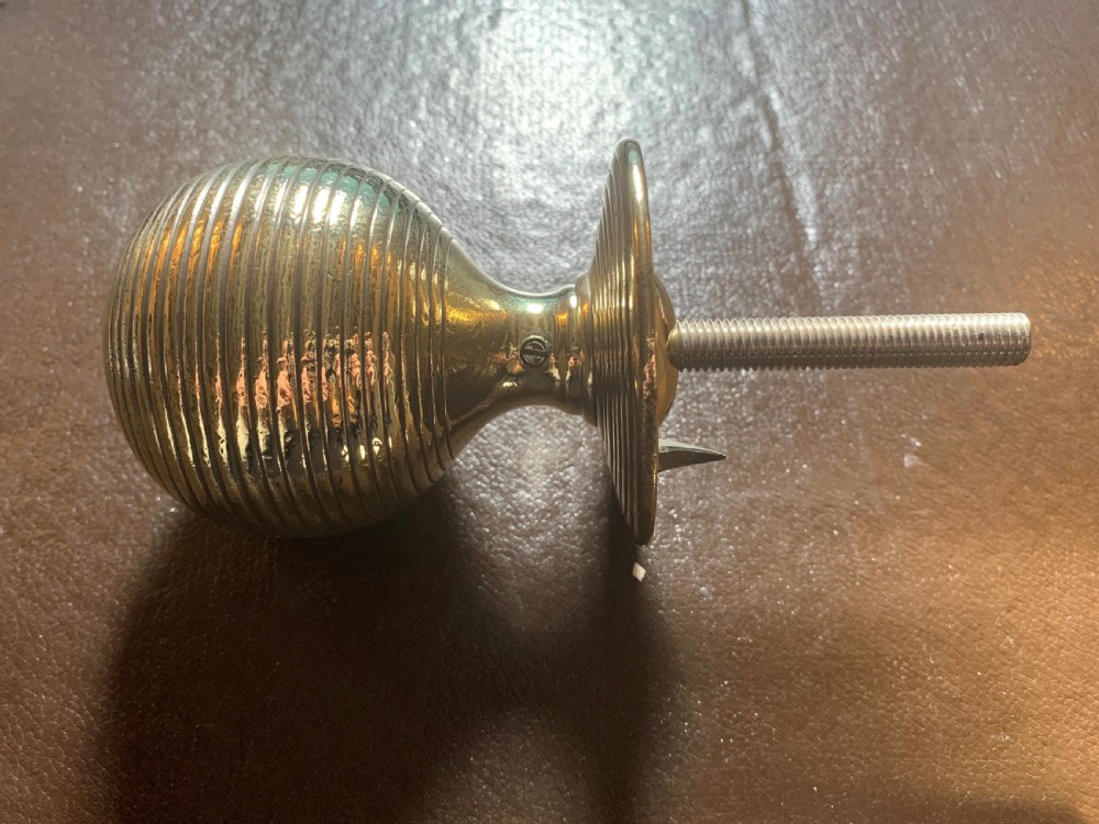 A solid brass Victorian beehive centre door knob with concentric reeded ridges and an attached mounting bolt. View II