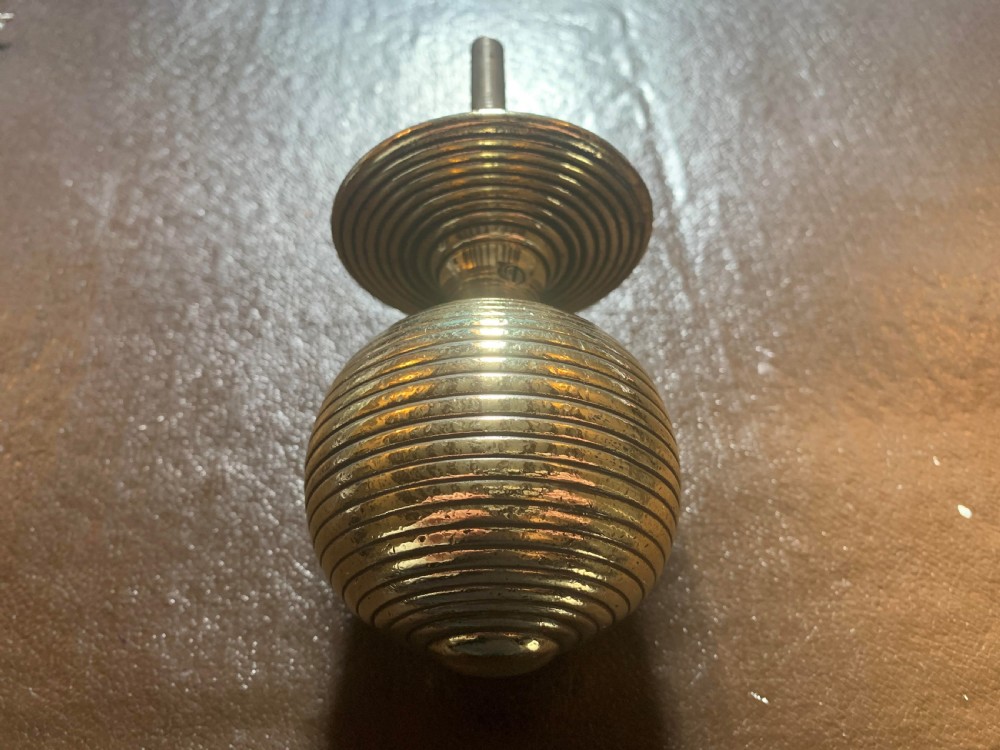 A solid brass Victorian beehive centre door knob with concentric reeded ridges and an attached mounting bolt. View III