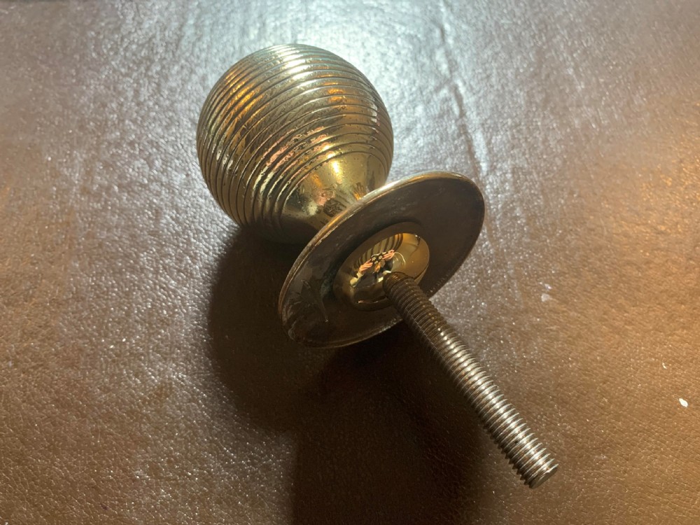 A solid brass Victorian beehive centre door knob with concentric reeded ridges and an attached mounting bolt. View IV