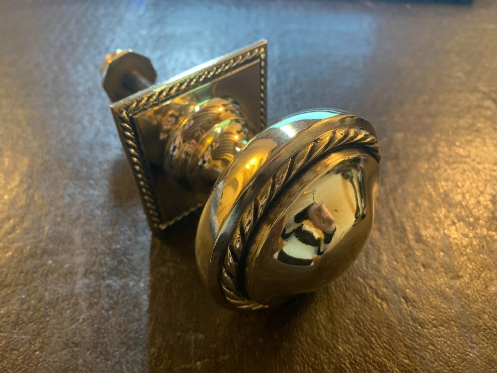 A polished Victorian brass centre door knob featuring a circular knob with a rope-twist border mounted on a square backplate.