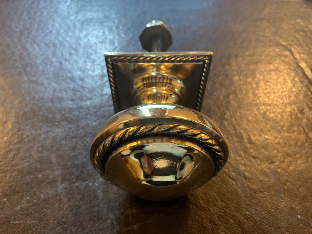A polished Victorian brass centre door knob featuring a circular knob with a rope-twist border mounted on a square backplate. View III