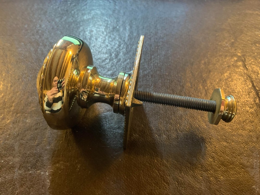 A polished Victorian brass centre door knob featuring a circular knob with a rope-twist border mounted on a square backplate. View IV