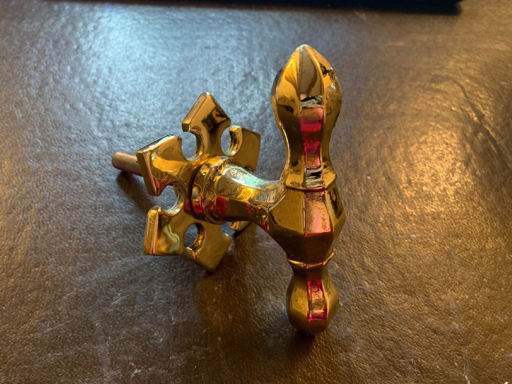 A polished brass Victorian centre door knob featuring a pointed T-bar handle and an ornate star-shaped rosette backplate with a threaded mounting bolt.