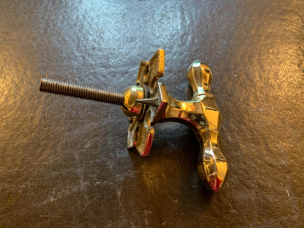 A polished brass Victorian centre door knob featuring a pointed T-bar handle and an ornate star-shaped rosette backplate with a threaded mounting bolt. View IV