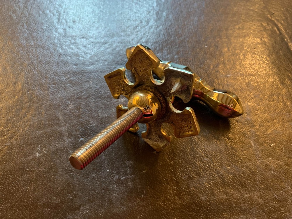 A polished brass Victorian centre door knob featuring a pointed T-bar handle and an ornate star-shaped rosette backplate with a threaded mounting bolt. View V