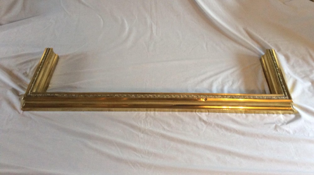 A rectangular three-sided Victorian brass fireplace fender with moulded decorative trim along the top edge.
