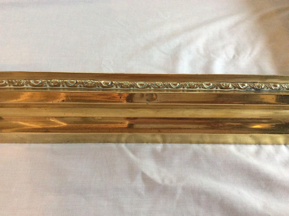 A rectangular three-sided Victorian brass fireplace fender with moulded decorative trim along the top edge. View III