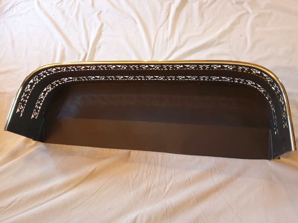 A Victorian brass fireplace fender featuring pierced fretwork patterns, rounded corners, and turned feet. View III