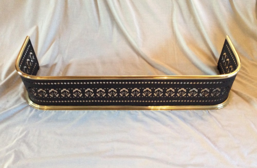 A Victorian black steel fireplace fender featuring a pierced geometric fretwork pattern framed by polished brass top and bottom rails. View III