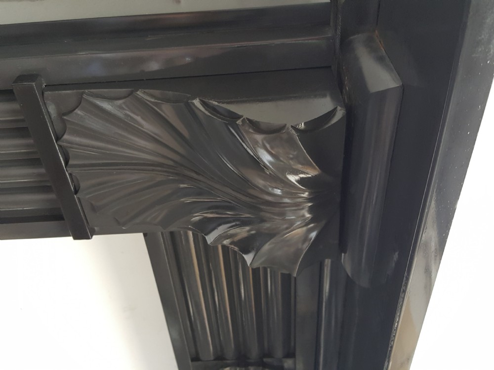 A black Victorian Welsh slate fireplace surround featuring fluted side jambs, carved fan brackets, and a central floral rosette motif. View III
