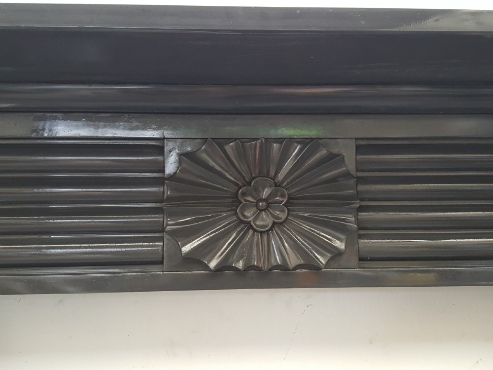 A black Victorian Welsh slate fireplace surround featuring fluted side jambs, carved fan brackets, and a central floral rosette motif. View IV