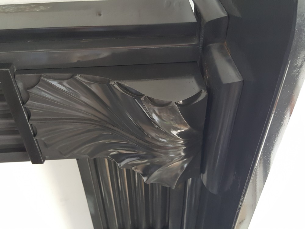 A black Victorian Welsh slate fireplace surround featuring fluted side jambs, carved fan brackets, and a central floral rosette motif. View V