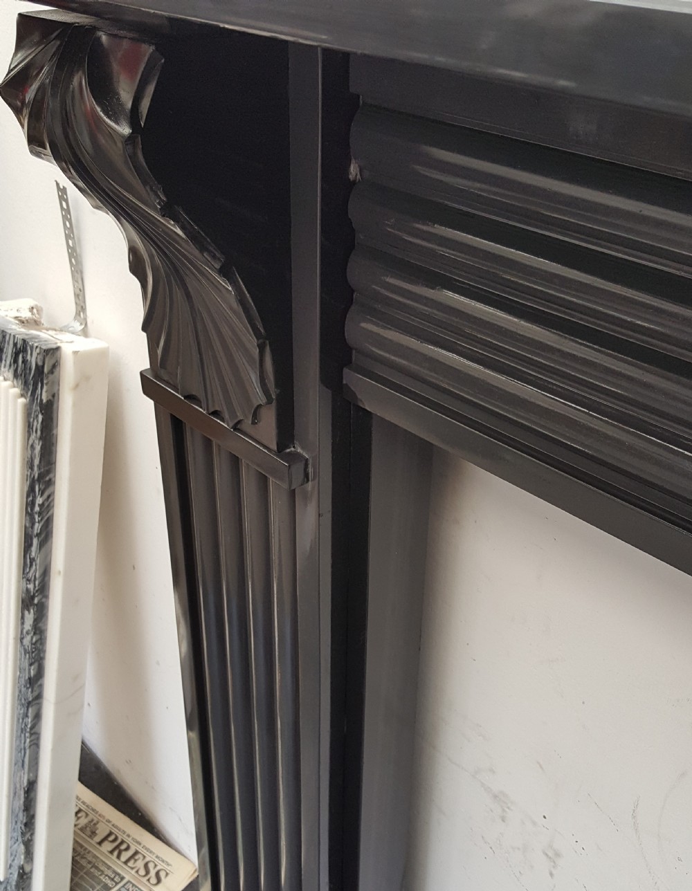 A black Victorian Welsh slate fireplace surround featuring fluted side jambs, carved fan brackets, and a central floral rosette motif. View VII
