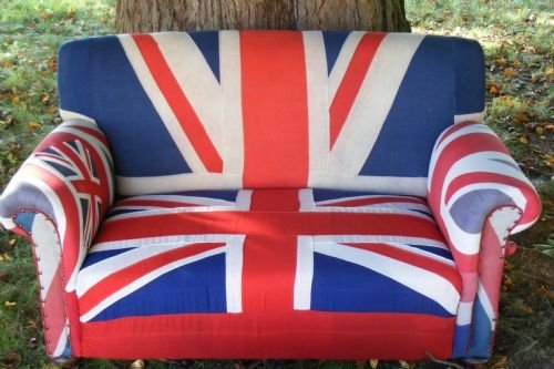 fig 1. A two-seater Howard style drop arm sofa upholstered in a bold red, white, and blue Union Jack flag fabric.