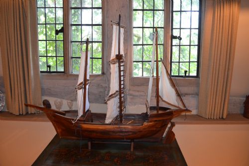 fig 1. A carved wooden three-masted model sailing boat with cream fabric sails and cord rigging.