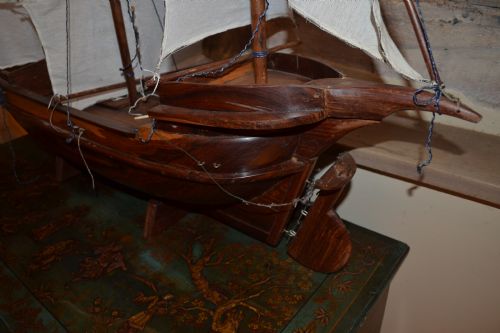 fig 3. A carved wooden three-masted model sailing boat with cream fabric sails and cord rigging.