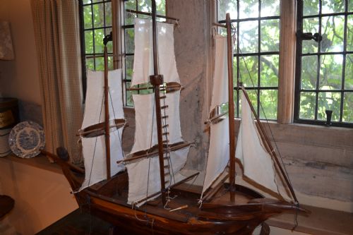 fig 4. A carved wooden three-masted model sailing boat with cream fabric sails and cord rigging.