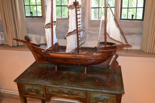fig 2. A carved wooden three-masted model sailing boat with cream fabric sails and cord rigging.