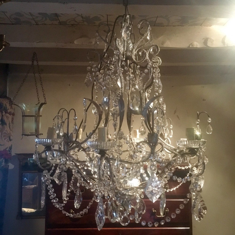 An ornate multi-tiered chandelier constructed with a scrolled metal frame adorned with cut crystal glass drops, beaded swags, and candle sleeve fittings. View II