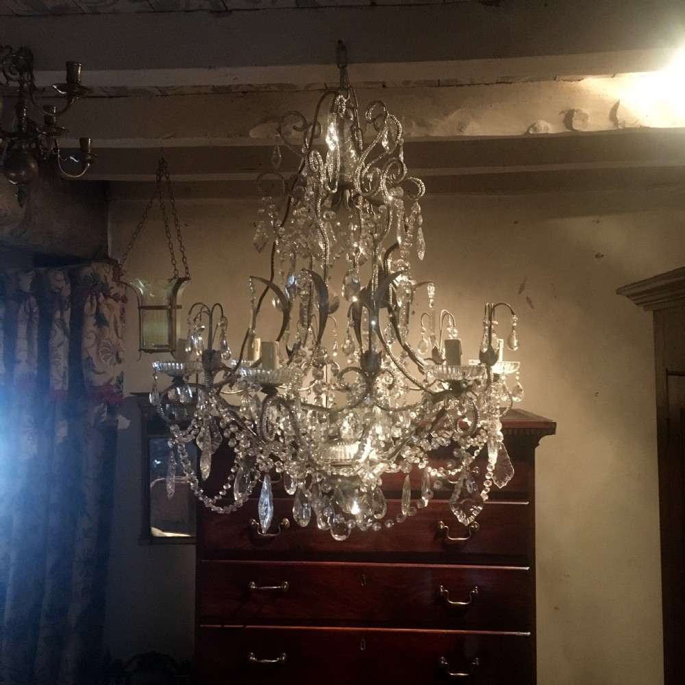 An ornate multi-tiered chandelier constructed with a scrolled metal frame adorned with cut crystal glass drops, beaded swags, and candle sleeve fittings. View III