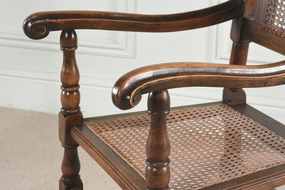 A pair of 17th-century style dark oak dining chairs with woven cane backrest panels, turned legs, and carved cresting rails. View IX