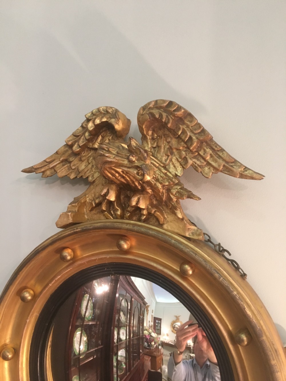 A circular Regency giltwood convex mirror featuring a carved eagle surmount, ball ornamentation along the moulded frame, an ebonised inner slip, and a carved pendant base. View III