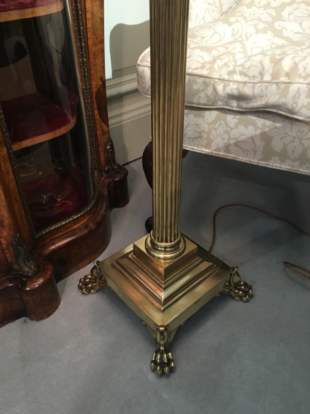 A brass telescopic standard lamp featuring a fluted column stem, Corinthian capital detail, a square stepped base with ornate feet, and a pleated white shade. View V