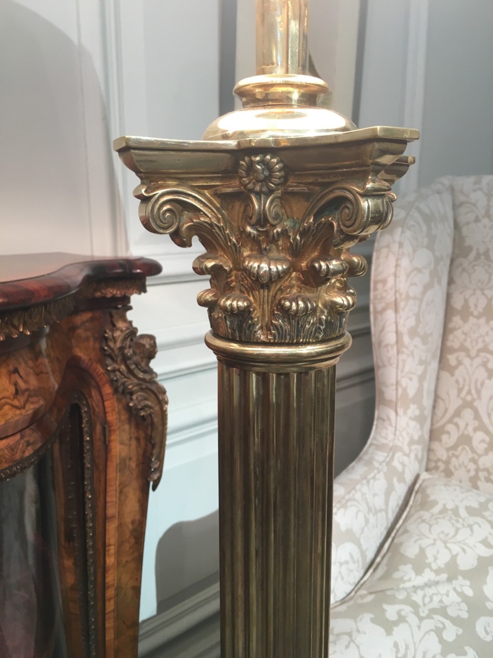 A brass telescopic standard lamp featuring a fluted column stem, Corinthian capital detail, a square stepped base with ornate feet, and a pleated white shade. View VII