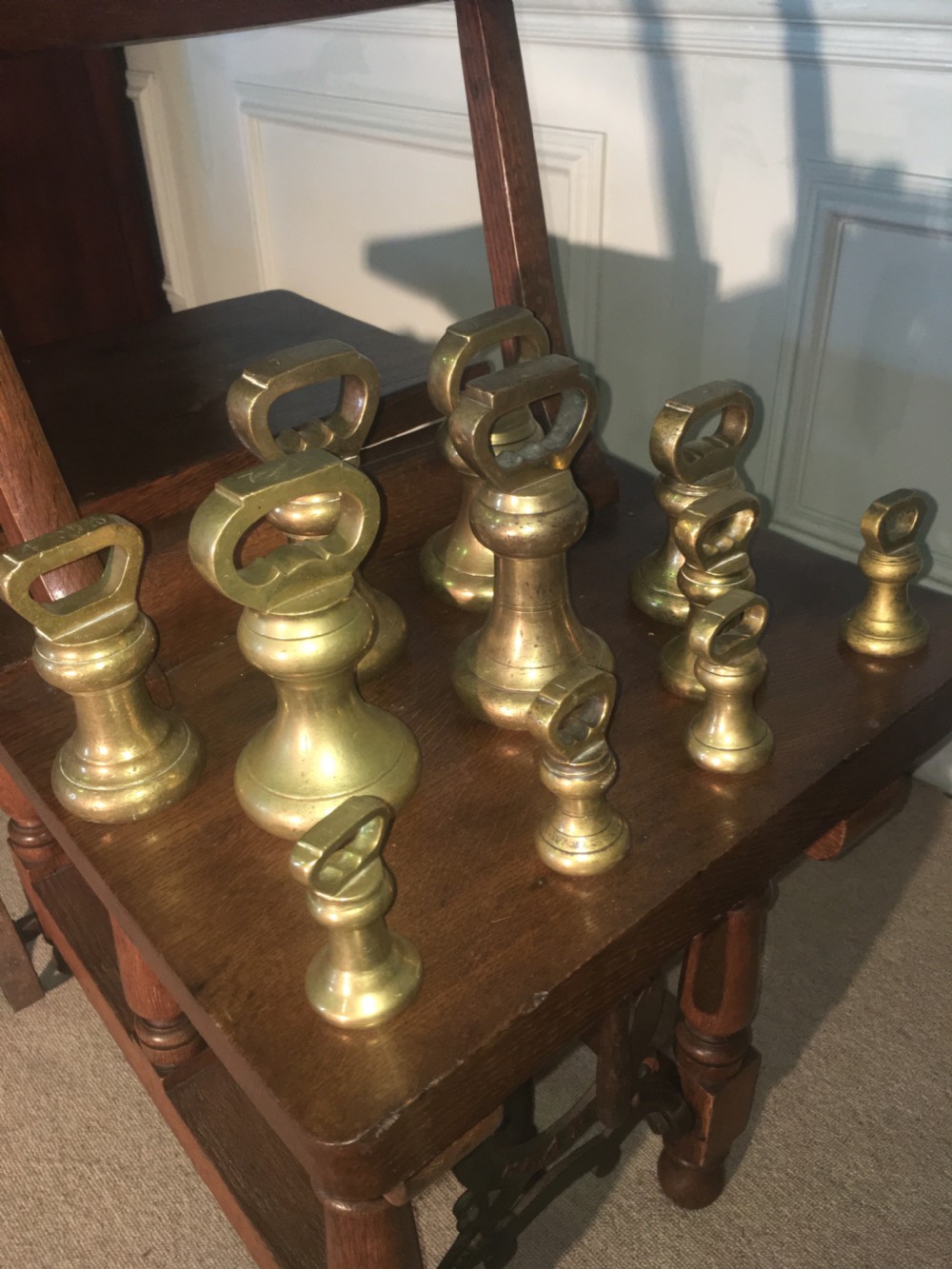 An antique oak jockey scale chair by Young & Son featuring turned legs, rear wheels, a brass balance mechanism, and a set of bell-shaped brass weights. View XII
