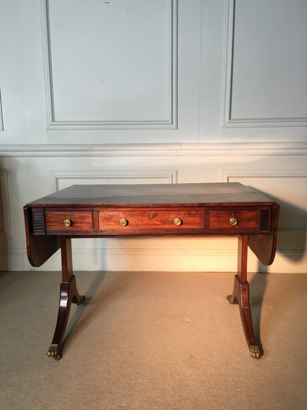 A Georgian mahogany sofa table with two drop leaves, front drawers with brass knobs, and splayed legs ending in brass claw castors. View III