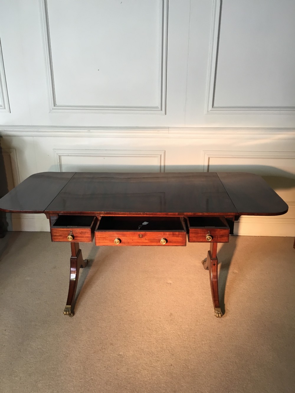 A Georgian mahogany sofa table with two drop leaves, front drawers with brass knobs, and splayed legs ending in brass claw castors. View VI