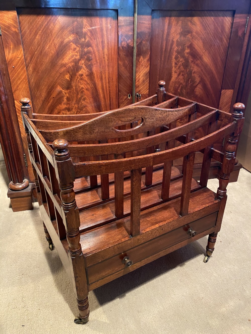 A George III mahogany canterbury featuring four slatted compartments, a single base drawer with brass knobs, and turned legs with brass castors. View II