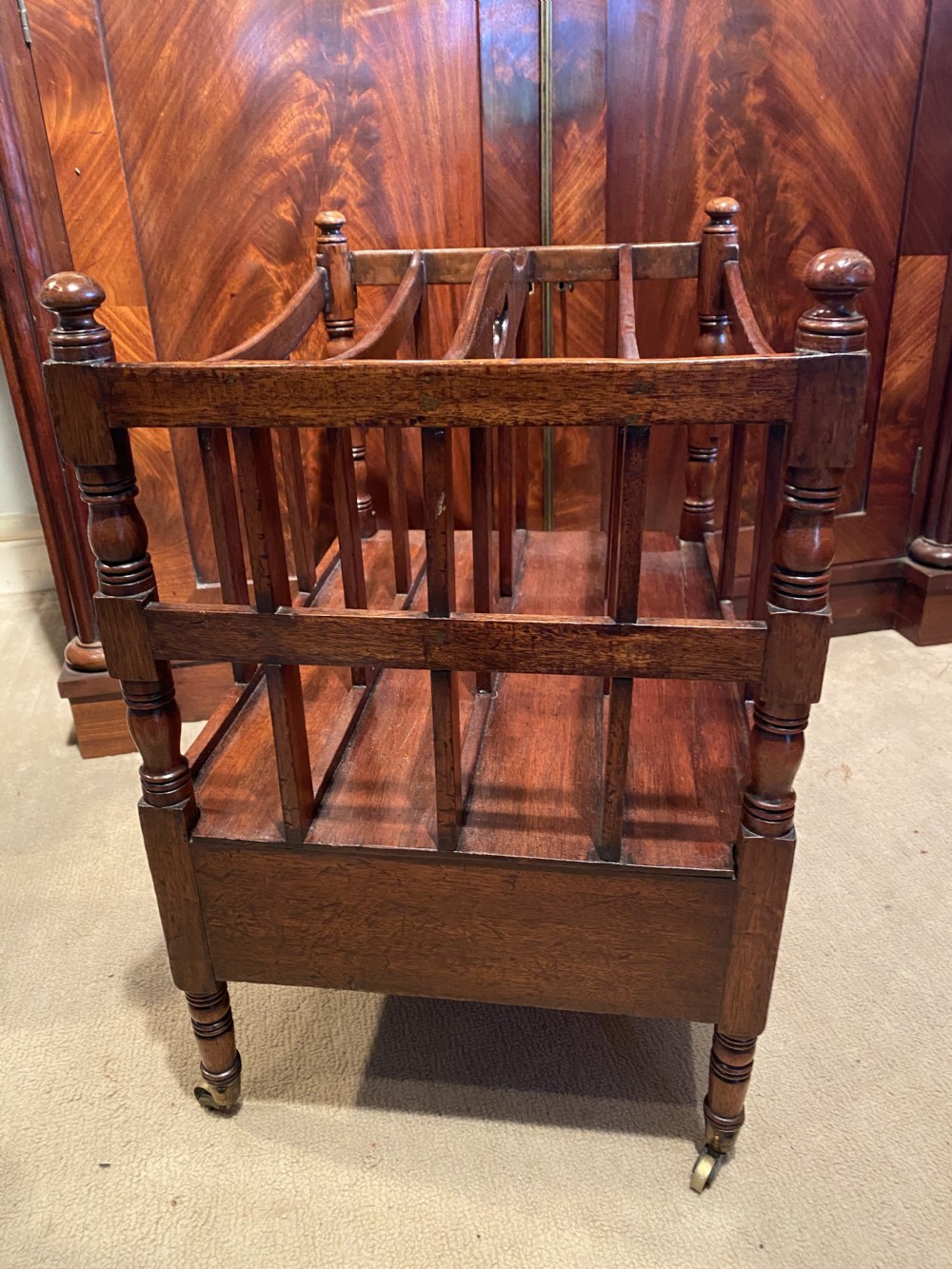 A George III mahogany canterbury featuring four slatted compartments, a single base drawer with brass knobs, and turned legs with brass castors. View III
