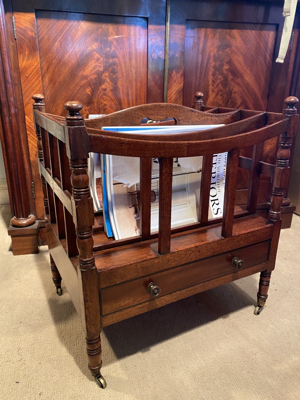 A George III mahogany canterbury featuring four slatted compartments, a single base drawer with brass knobs, and turned legs with brass castors. View VI
