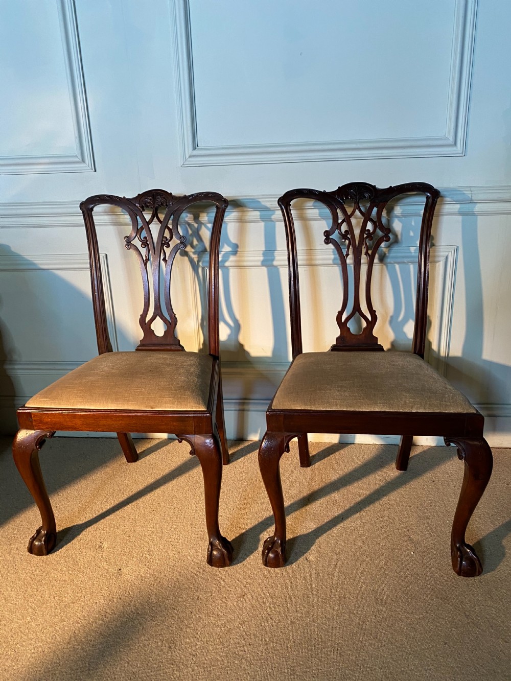 A pair of 19th-century Chippendale style dark mahogany dining chairs featuring carved pierced back splats, upholstered seats, and cabriole front legs ending in ball and claw feet. View III