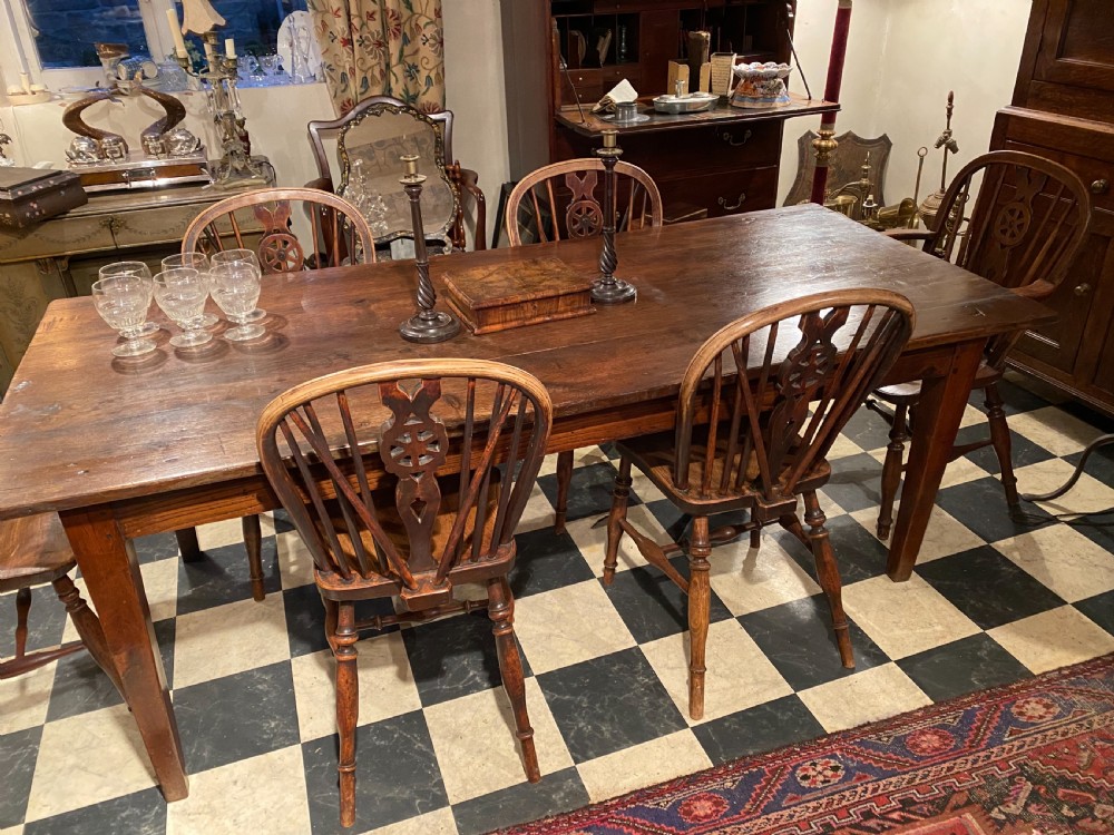 A set of antique wooden Windsor dining chairs featuring hoop backs, wheelback carved splats, spindle supports, shaped saddle seats, and turned legs. View II