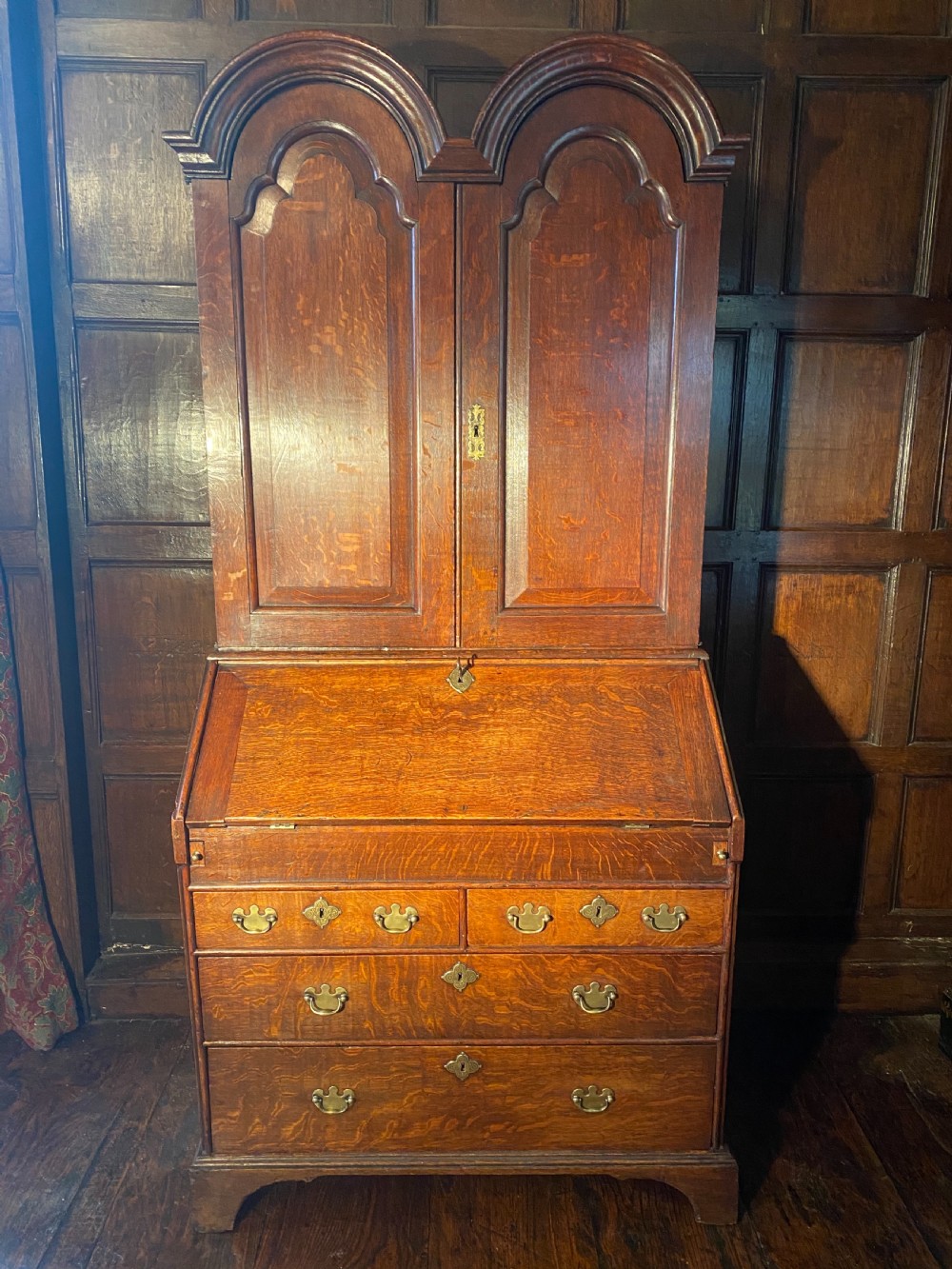 A George I period oak double-dome bureau cabinet featuring double arched panel doors above a sloping fall-front writing desk and graduated drawers with brass handles. View III
