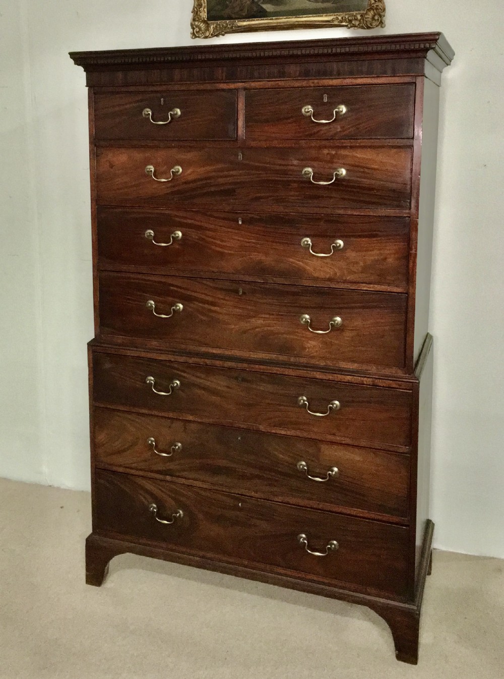 An 18th-century George III flame mahogany chest on chest featuring two short over five long drawers with brass handles and bracket feet.