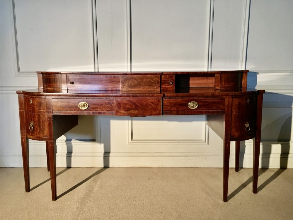 A George III mahogany sideboard featuring a stage top superstructure, boxwood inlay, brass ring handles, and square tapered legs. View II