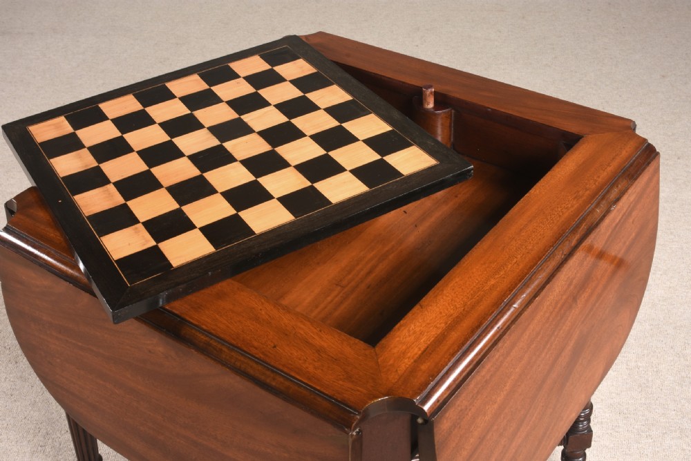 A 19th-century mahogany games table featuring a square top with an inlaid chessboard, two drop-leaf sides, reeded turned legs, and an X-stretcher with a central finial. View V
