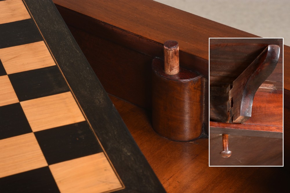 A 19th-century mahogany games table featuring a square top with an inlaid chessboard, two drop-leaf sides, reeded turned legs, and an X-stretcher with a central finial. View VI