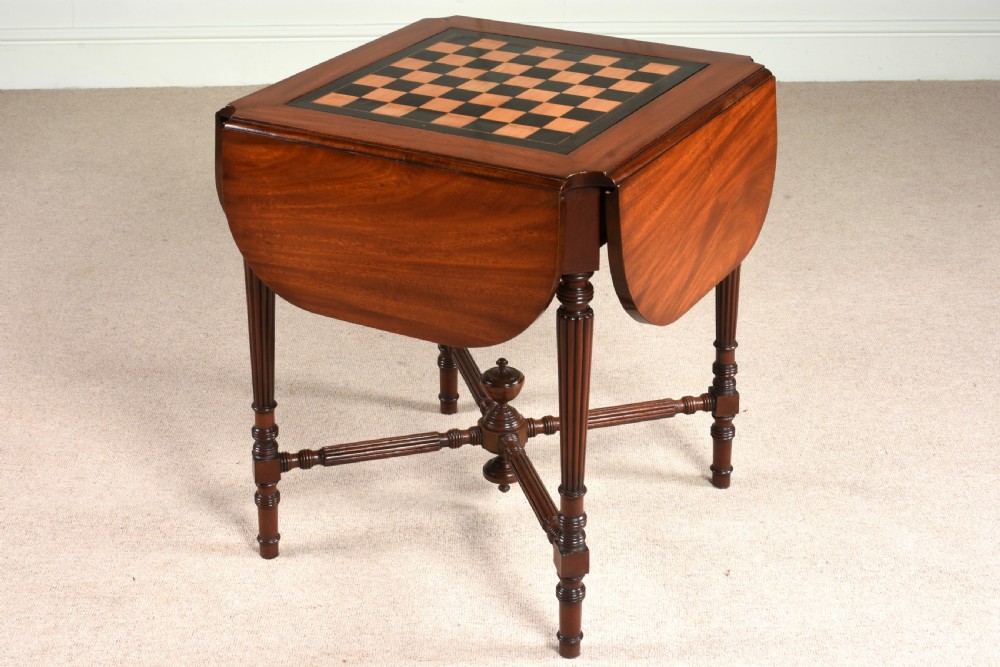A 19th-century mahogany games table featuring a square top with an inlaid chessboard, two drop-leaf sides, reeded turned legs, and an X-stretcher with a central finial. View XIII