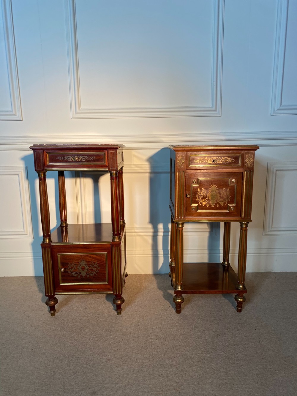 A pair of French Empire mahogany bedside cabinets featuring marble tops, inlaid brass classical foliage motifs, fluted column supports, and single cupboard doors. View III